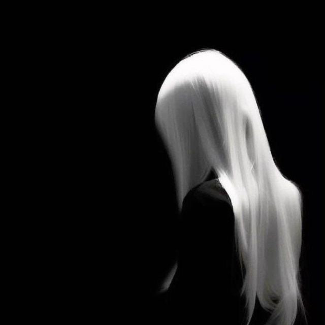 Person with long white hair against a black background